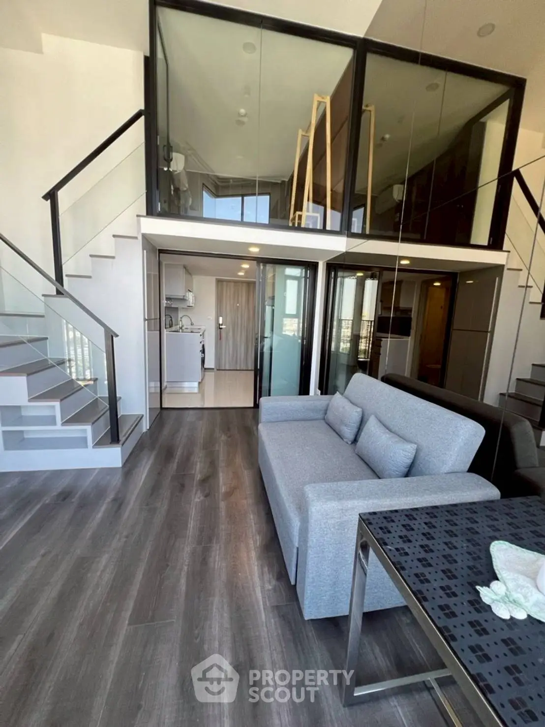 Modern duplex apartment with sleek design and spacious living area, featuring a stylish staircase and glass partitions.