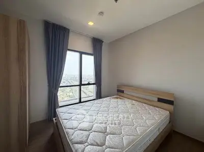 Spacious bedroom with large window offering stunning city views, featuring a comfortable bed and modern decor.