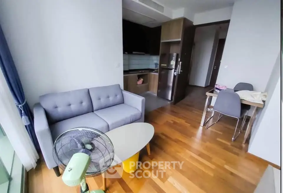 Modern living room with cozy sofa and open kitchen layout in stylish apartment.
