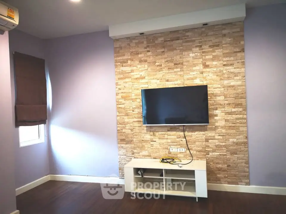 Modern living room with mounted TV and stylish stone accent wall.