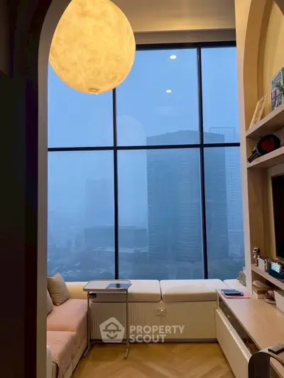 Modern living room with large window offering stunning city view, cozy seating, and elegant lighting.