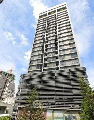Modern high-rise building with sleek architectural design and lush greenery.