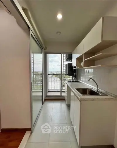 Modern kitchen with sleek cabinetry and balcony view in a stylish apartment.