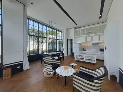 Luxurious open-layout living room with high ceilings and elegant kitchen area, featuring large windows and stylish decor.