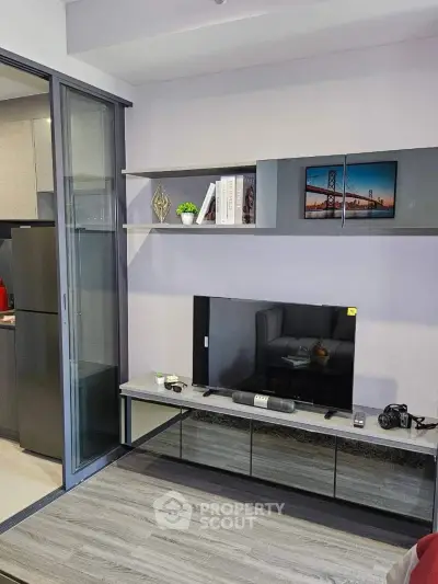 Modern living room with sleek TV unit and sliding glass door to kitchen