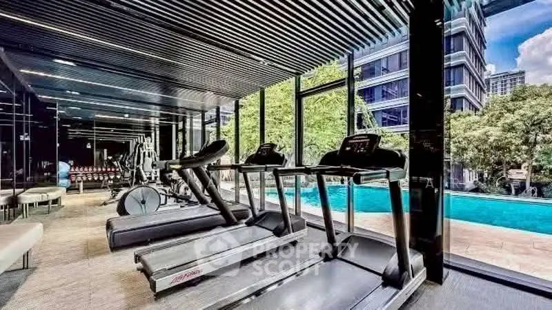 Luxurious gym with modern equipment and pool view in upscale residential building.