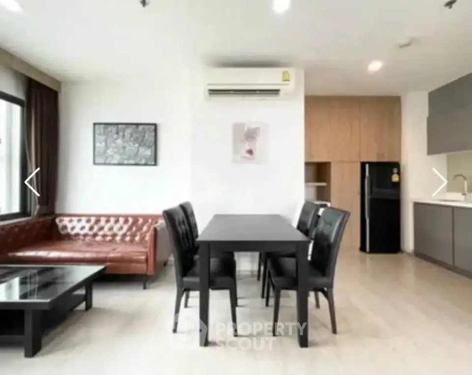 Modern open-layout living room with dining area and sleek kitchen in a stylish apartment.