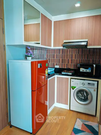 Modern kitchen with red fridge, washing machine, and sleek cabinetry