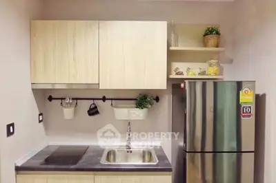 Modern kitchen with sleek cabinetry and stainless steel fridge in compact layout.