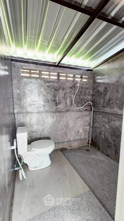 Modern minimalist bathroom with concrete walls and open roof design.