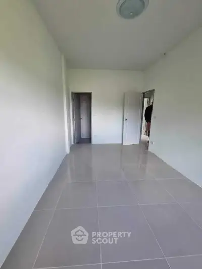 Spacious empty room with tiled flooring and white walls, ready for customization.