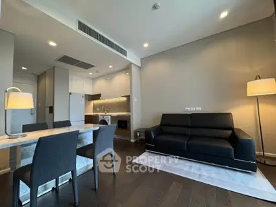 Modern living room with open kitchen, sleek black sofa, and elegant dining area in a stylish apartment.