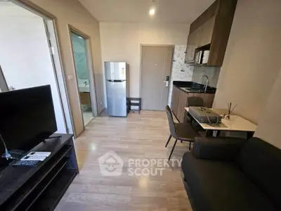 Modern apartment interior with compact kitchen and cozy living area, featuring sleek furniture and wooden flooring.