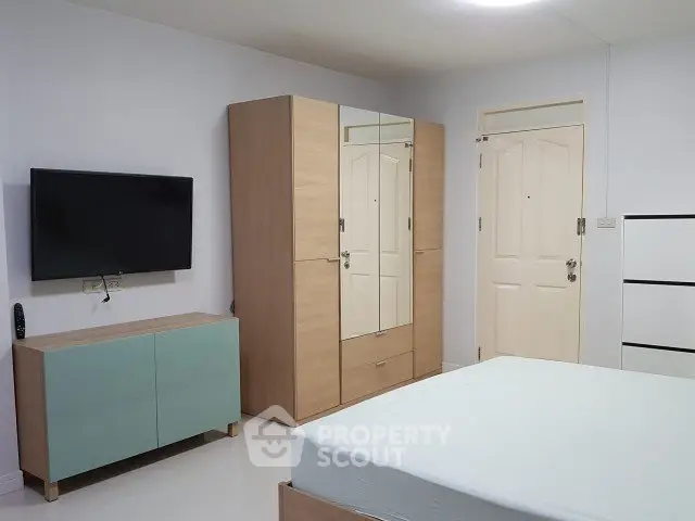 Modern bedroom with minimalist furniture and wall-mounted TV