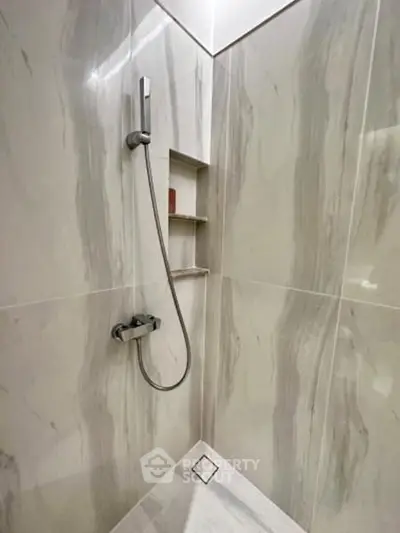 Modern bathroom shower with sleek marble tiles and built-in shelving