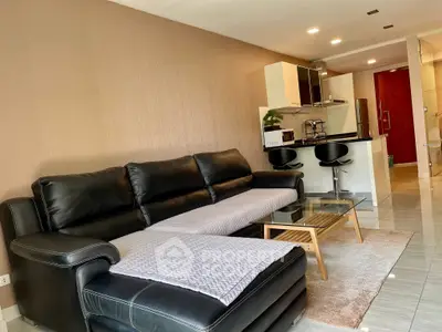 Modern living room with sleek black leather sofa and open kitchen layout