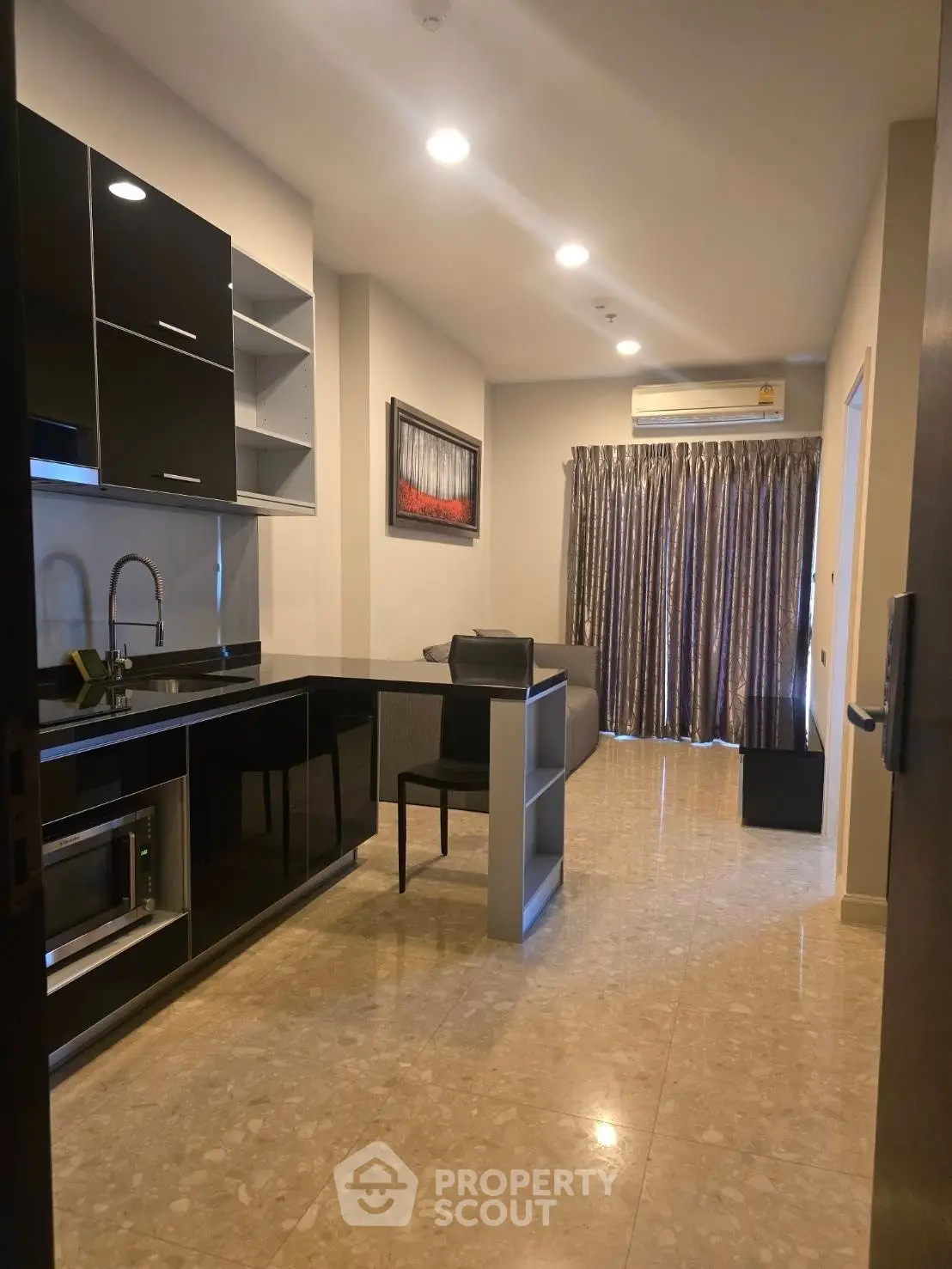 Modern open-layout kitchen with sleek black cabinets and cozy living area.