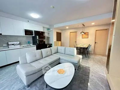 Modern open-layout living room with sleek kitchen and dining area, featuring stylish furniture and contemporary design.