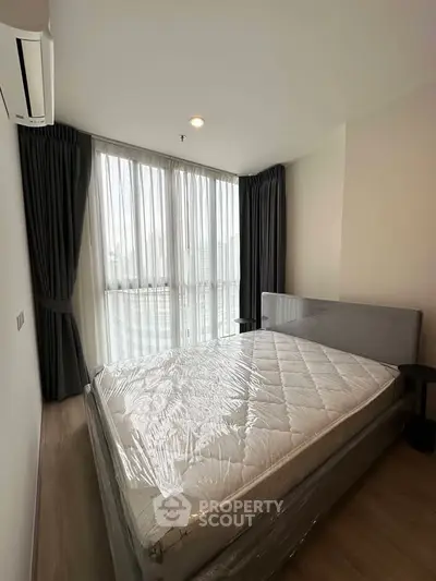 Modern bedroom with large windows and natural light in a stylish apartment.
