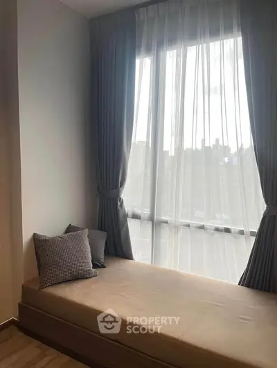 Cozy bedroom with large window and elegant curtains, perfect for relaxation.