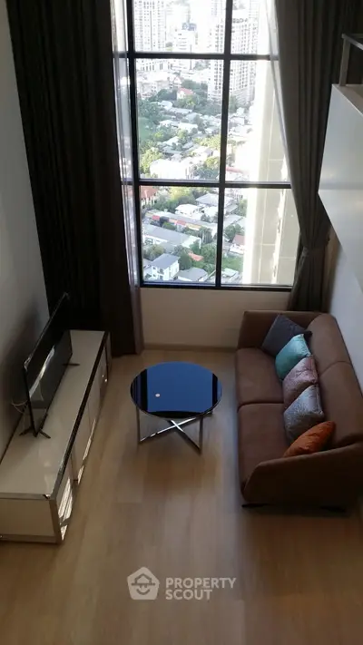 Modern living room with city view, featuring sleek furniture and large windows.