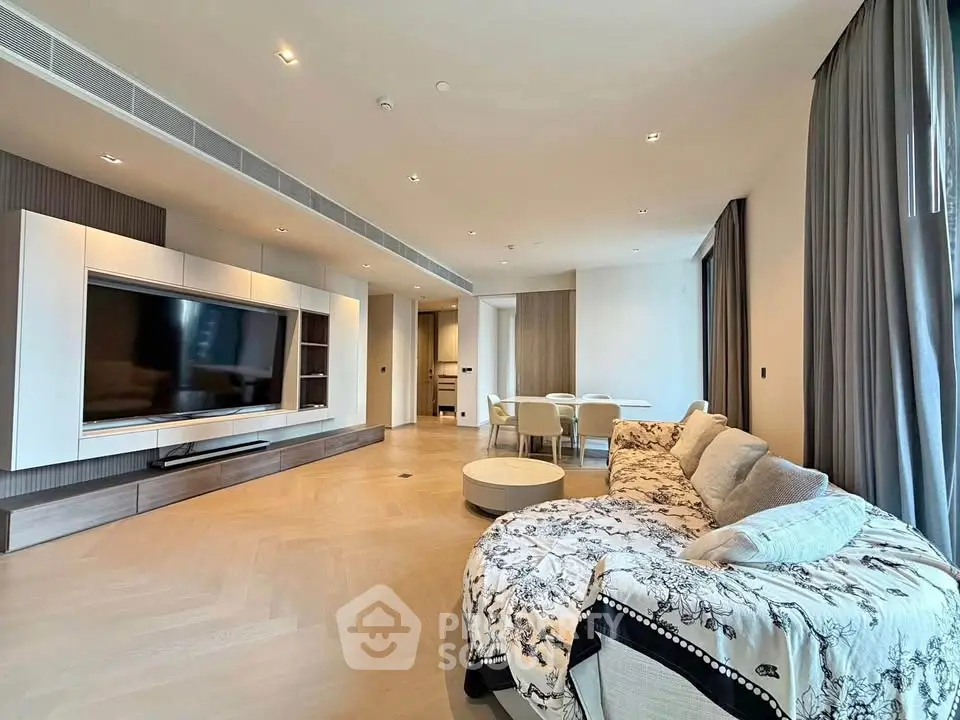 Spacious modern living room with elegant decor and large TV, perfect for relaxation and entertainment.