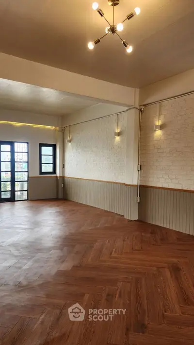 Spacious modern living room with elegant wooden flooring and stylish lighting.
