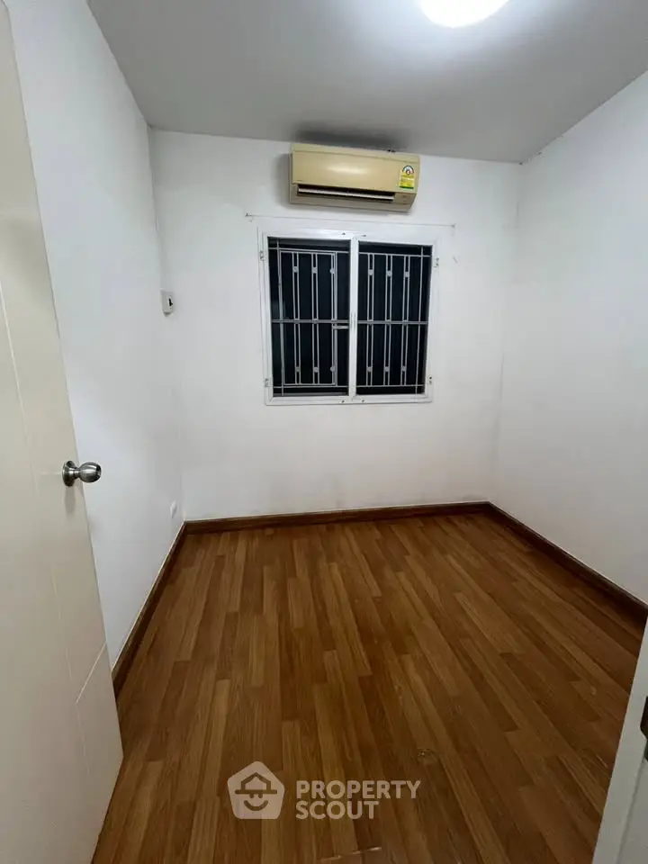 Cozy small room with wooden flooring and air conditioning, perfect for a compact living space.