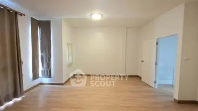 Spacious empty room with wooden flooring and natural light, ideal for customization.