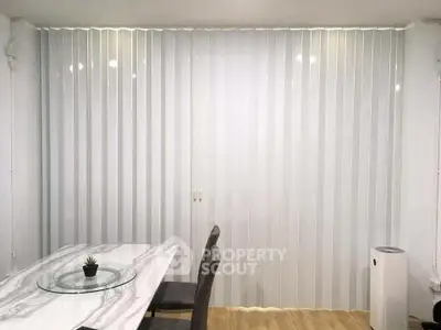Modern dining area with marble table and vertical blinds, perfect for stylish living.