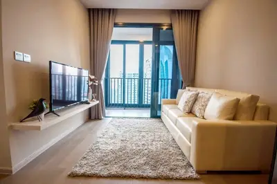 Modern living room with balcony view, cozy sofa, and sleek TV setup.