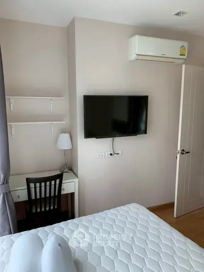 Modern bedroom with wall-mounted TV and air conditioning, featuring a cozy study corner.