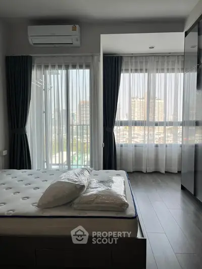 Modern bedroom with city view, featuring large windows and sleek design.