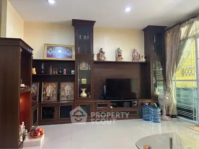 Spacious living room with elegant wooden entertainment center and natural light.