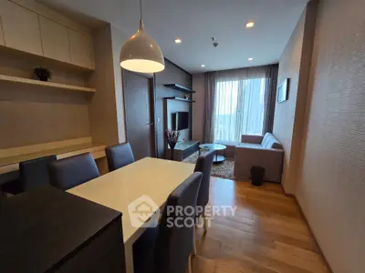 Modern living room with dining area, stylish furniture, and large window offering natural light.