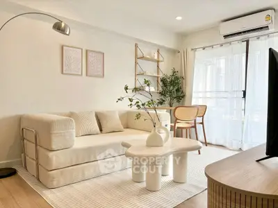 Stylish modern living room with cozy sofa, elegant decor, and natural light from large windows.
