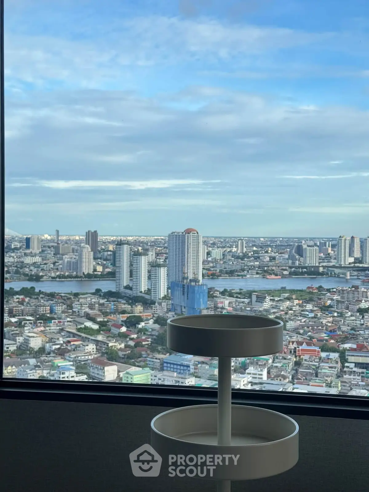 Stunning cityscape view from high-rise apartment window with modern decor.