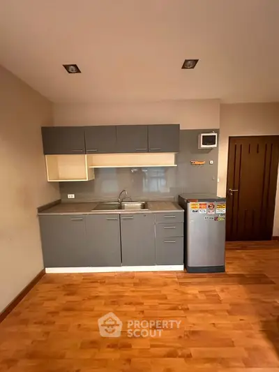 Modern kitchen with sleek cabinets and compact fridge in cozy apartment.