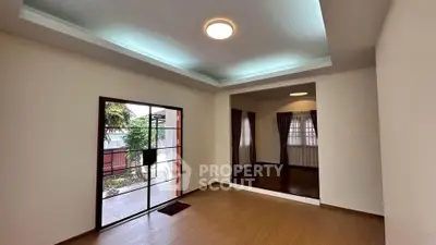 Spacious living room with wooden flooring and large window overlooking garden.