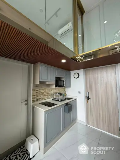 Modern compact kitchen with sleek cabinetry and built-in appliances in a stylish apartment.