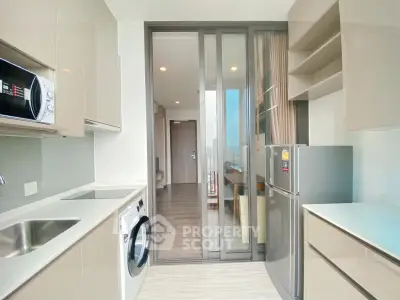 Modern kitchen with sleek cabinetry, washing machine, and stainless steel appliances in a bright apartment.