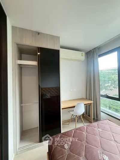 Modern bedroom with built-in closet and study desk, featuring large window with natural light.