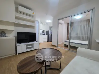 Modern living room with open layout, featuring sleek furniture and a view into a cozy bedroom.