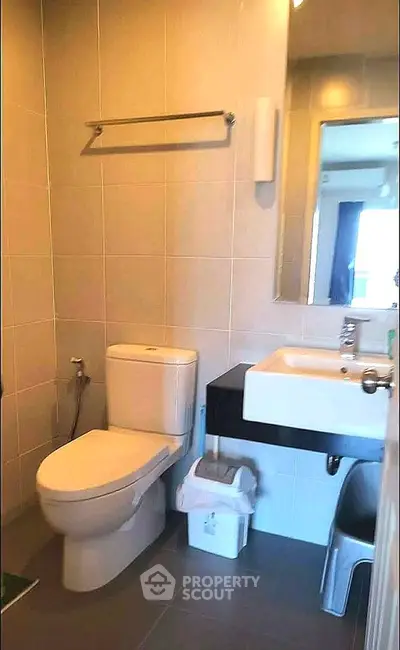 Modern bathroom with sleek fixtures and neutral tiles, featuring a toilet and sink.