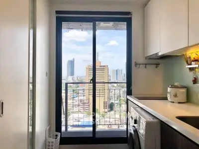 Modern kitchen with city view, featuring washing machine and sleek cabinetry.