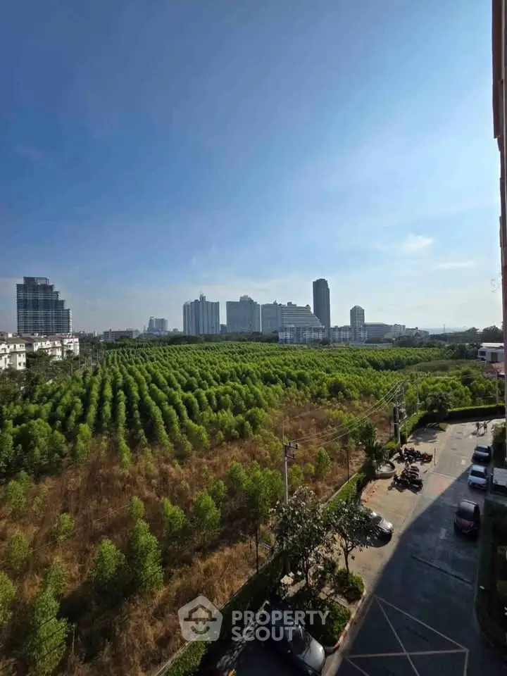Scenic view of lush green landscape with city skyline in the background.
