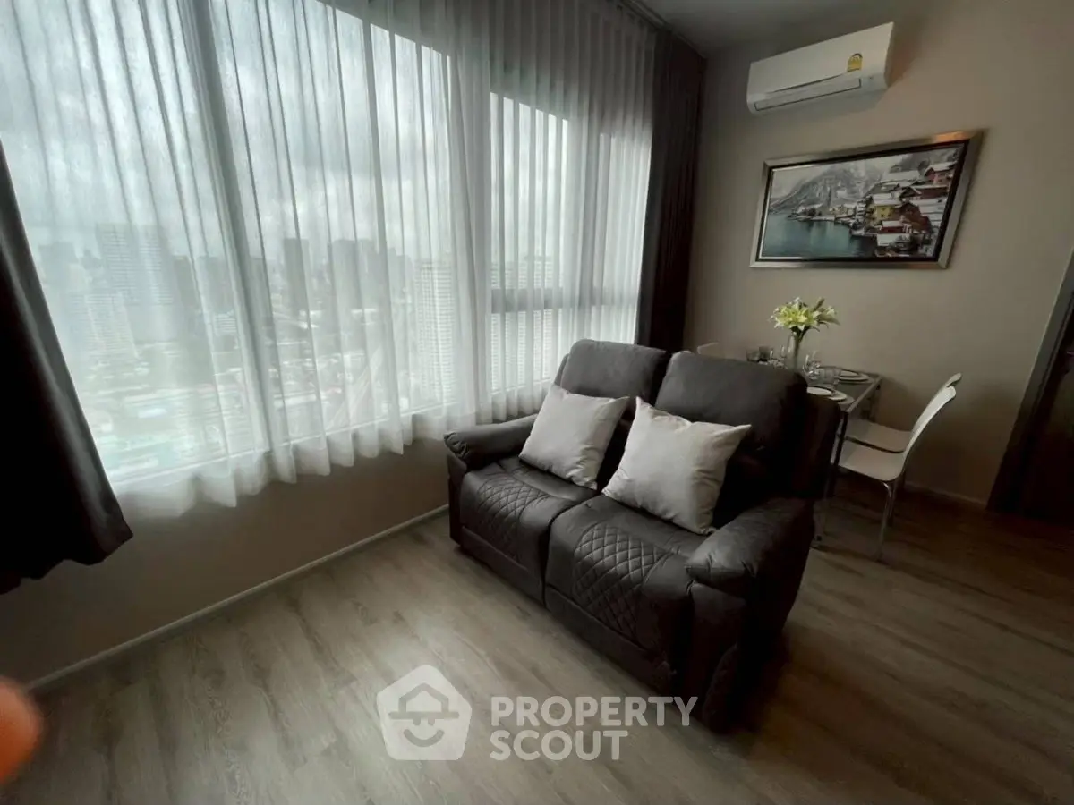 Cozy living room with city view, featuring a plush sofa and dining area, perfect for urban living.