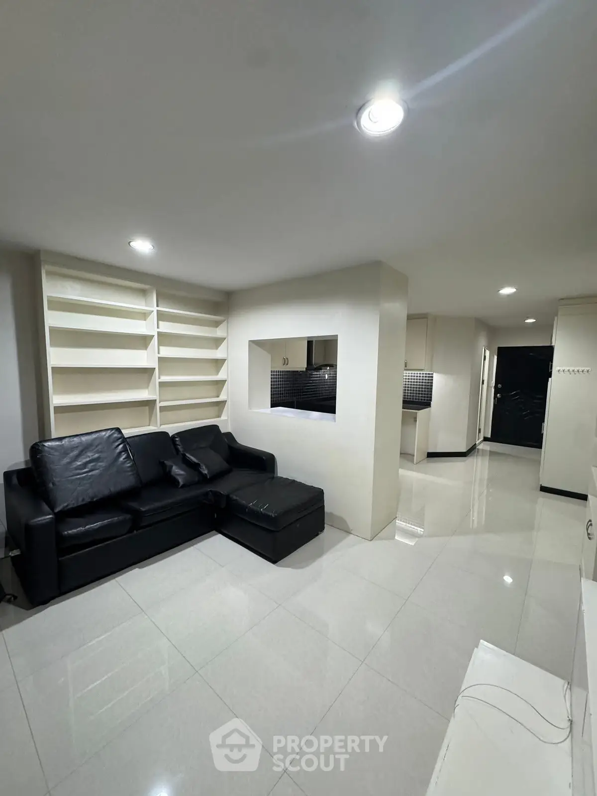 Modern living room with sleek black leather sofa and built-in shelves