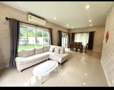 Spacious living room with modern furniture and large windows overlooking a garden.