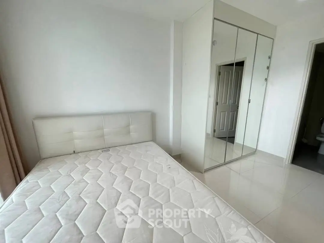 Spacious bedroom with mirrored wardrobe and comfortable bed in modern apartment.